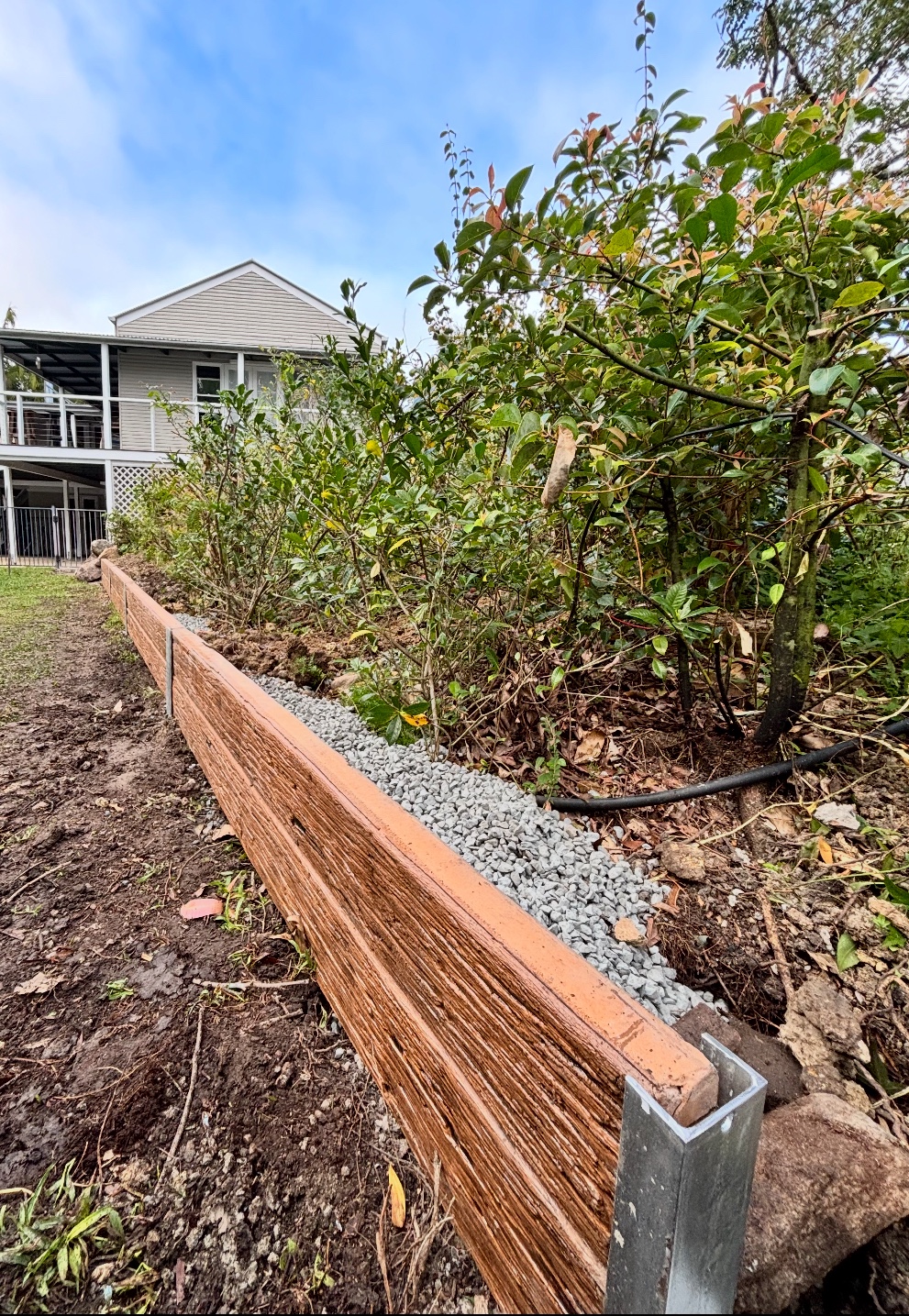 Concrete sleeper retaining wall with drainage gravel installed behind it